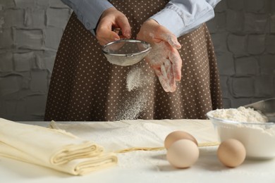 Woman making puff pastry dough at white table, closeup