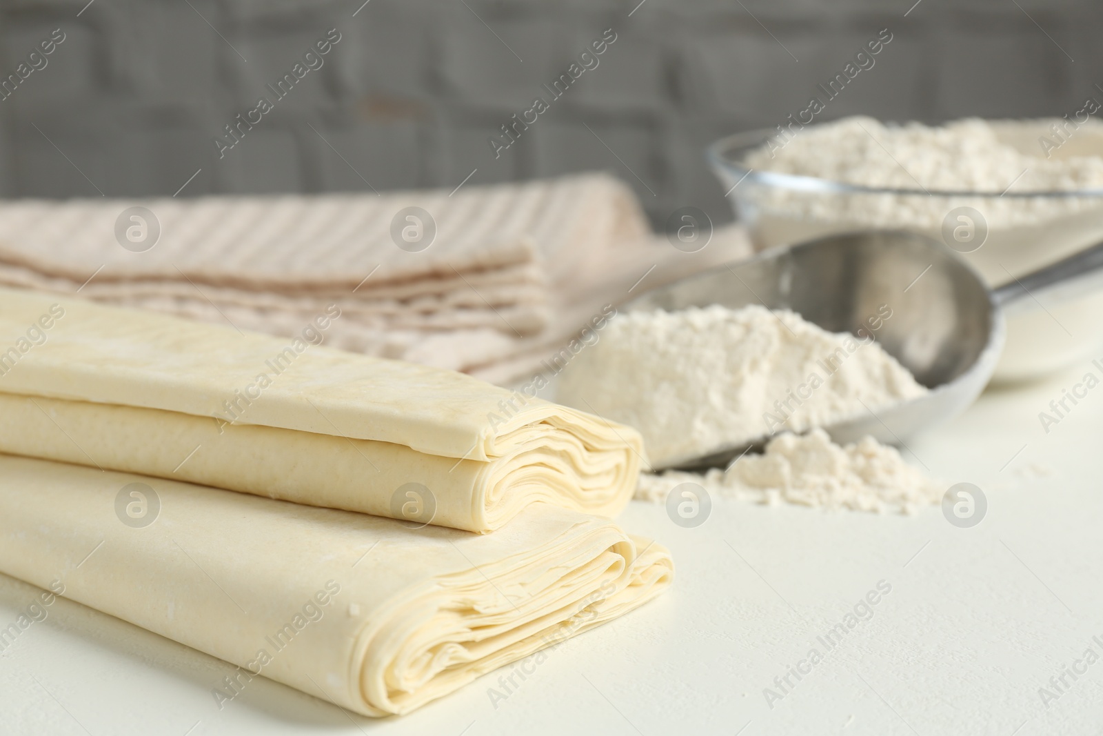 Photo of Raw puff pastry dough on white table, closeup. Space for text