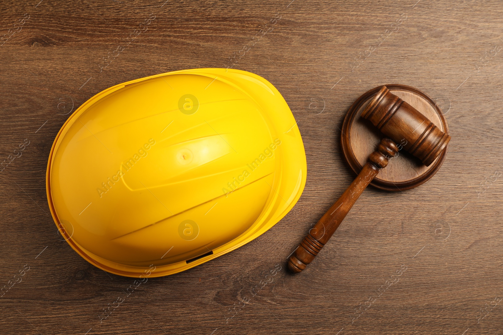 Photo of Accident at work concept. Gavel and hardhat on wooden table, top view