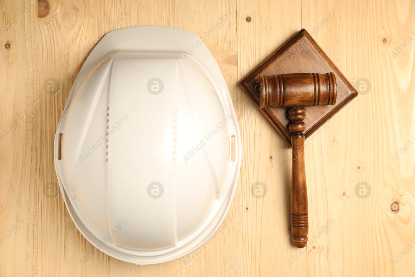 Photo of Accident at work concept. Gavel and hardhat on wooden table, top view