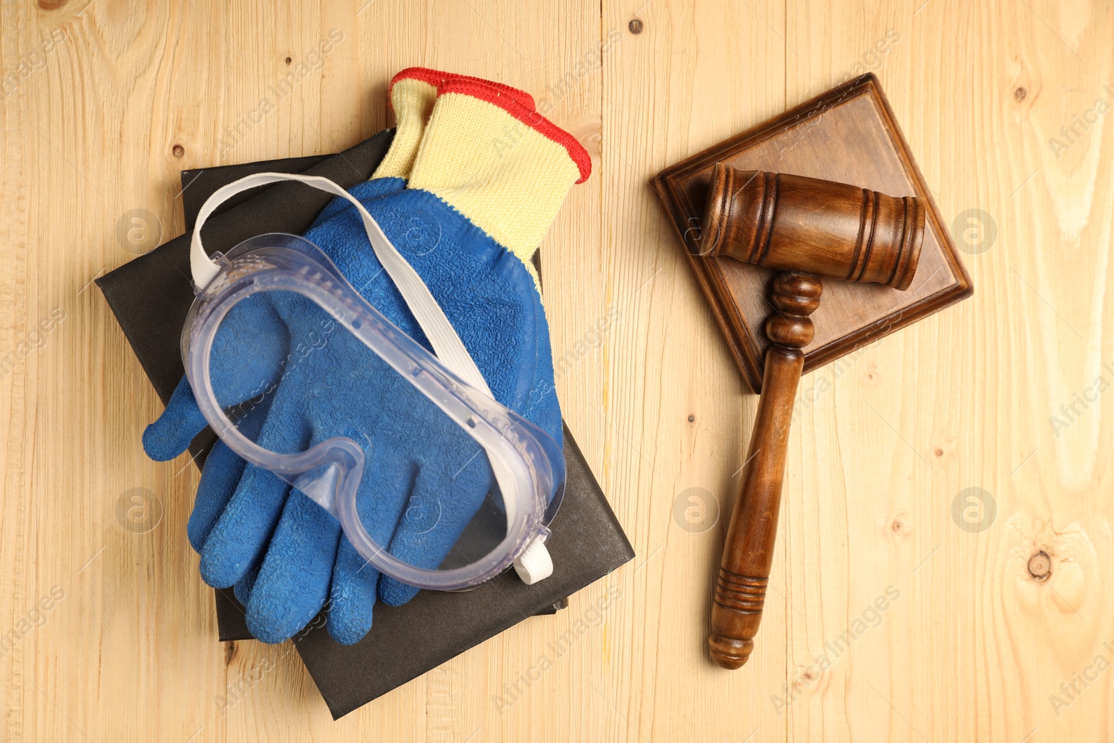 Photo of Accident at work concept. Gavel, books and protective gear on wooden table, flat lay