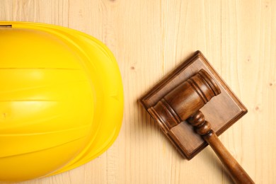 Photo of Accident at work concept. Gavel and hardhat on wooden table, top view