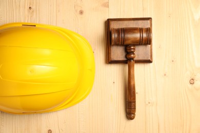 Photo of Accident at work concept. Gavel and hardhat on wooden table, top view