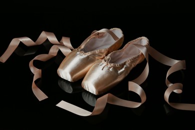 Photo of Pair of beautiful pointe shoes on black mirror surface