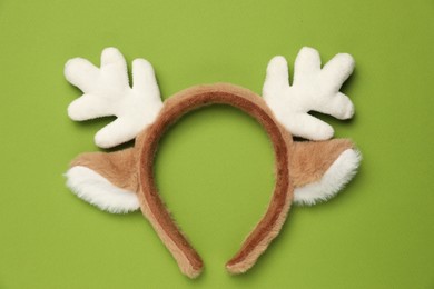 Photo of Beautiful reindeer headband on green background, top view. Christmas accessory