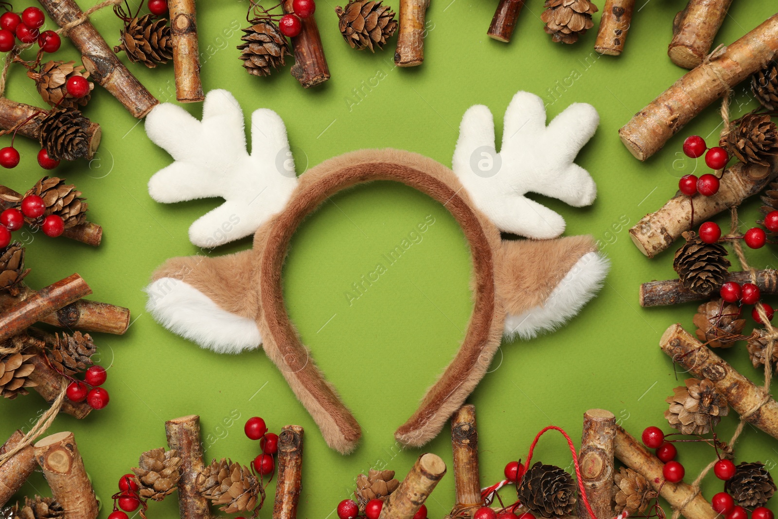 Photo of Beautiful reindeer headband and Christmas decor on green background, flat lay