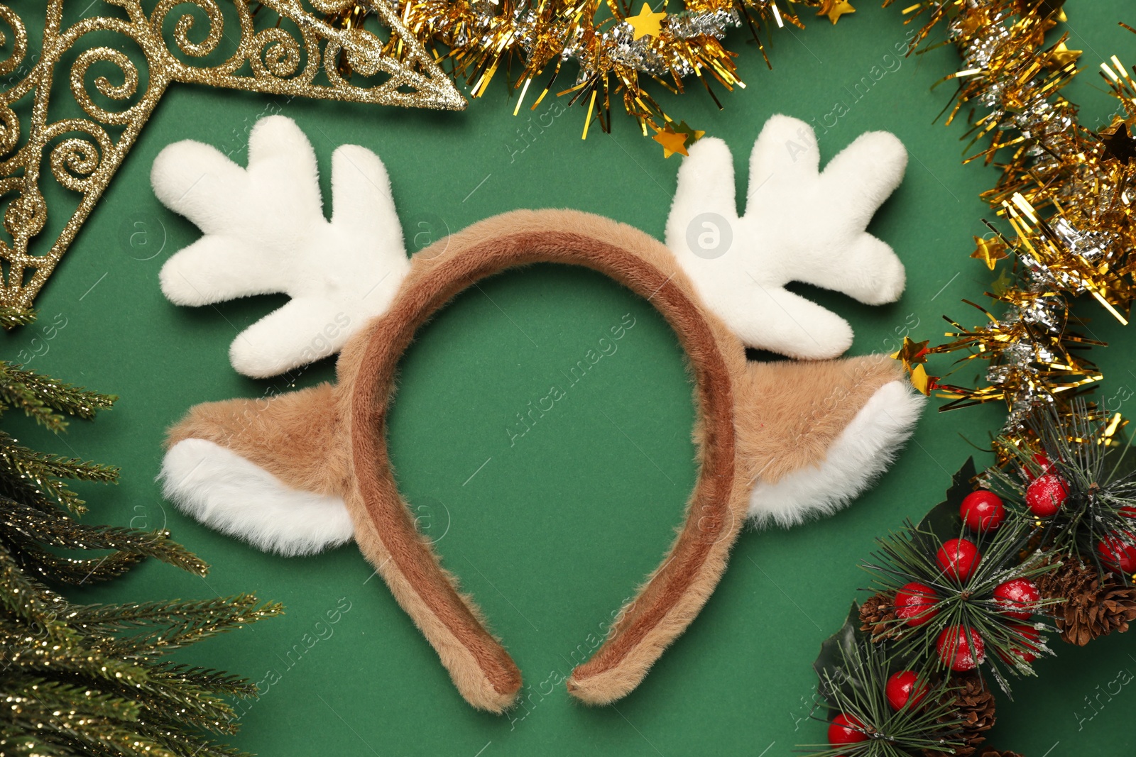 Photo of Beautiful reindeer headband and Christmas decor on green background, flat lay