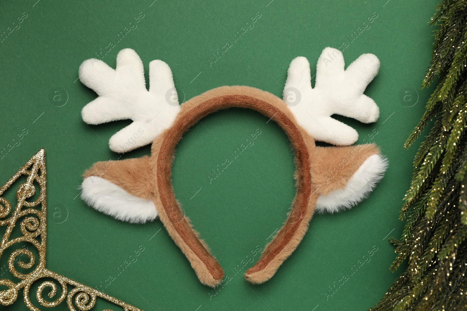 Photo of Beautiful reindeer headband and Christmas decor on green background, flat lay