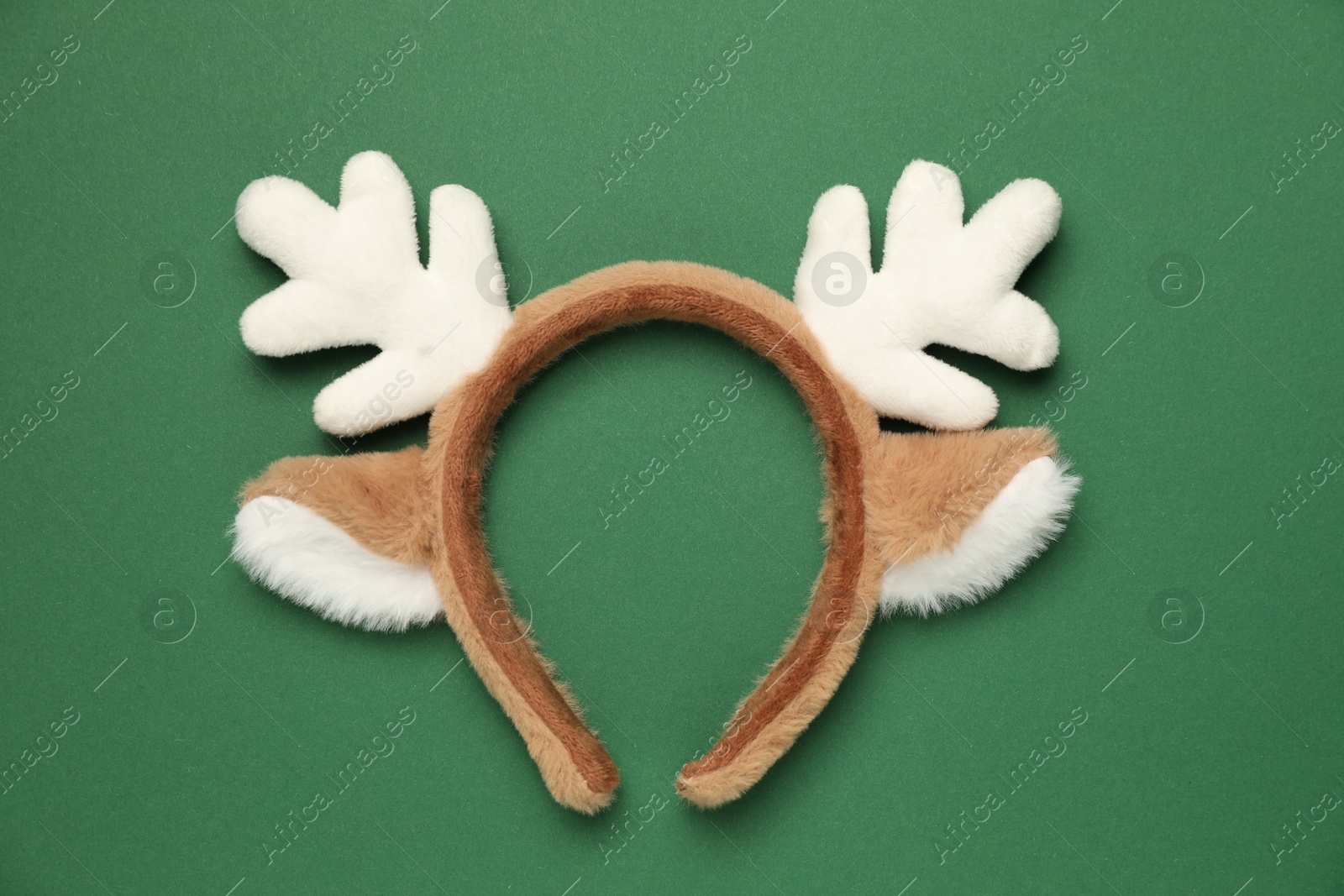 Photo of Beautiful reindeer headband on green background, top view. Christmas accessory