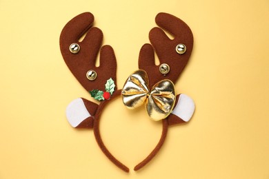 Photo of Beautiful reindeer headband on pale yellow background, top view. Christmas accessory