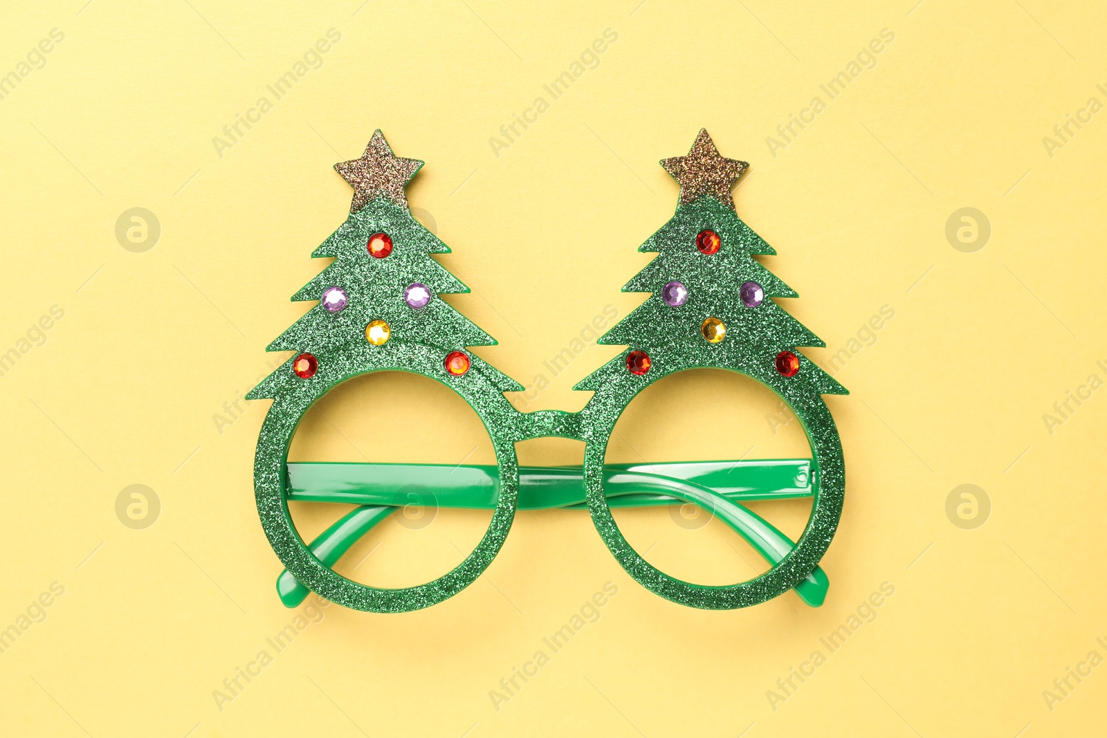 Photo of Funny party glasses on pale yellow background, top view. Christmas accessory