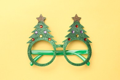 Photo of Funny party glasses on pale yellow background, top view. Christmas accessory