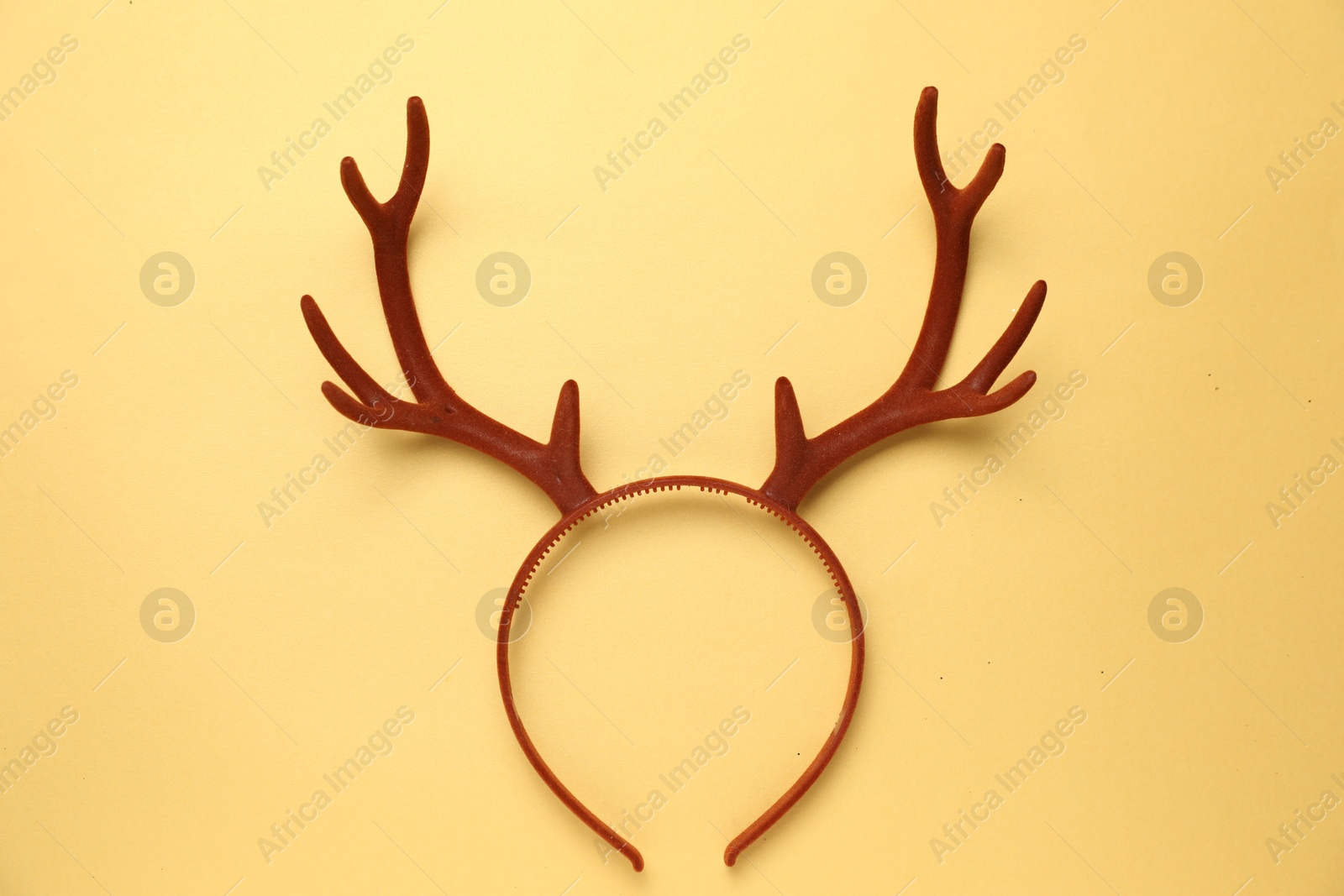 Photo of Beautiful reindeer headband on pale yellow background, top view. Christmas accessory