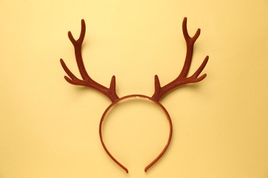 Photo of Beautiful reindeer headband on pale yellow background, top view. Christmas accessory