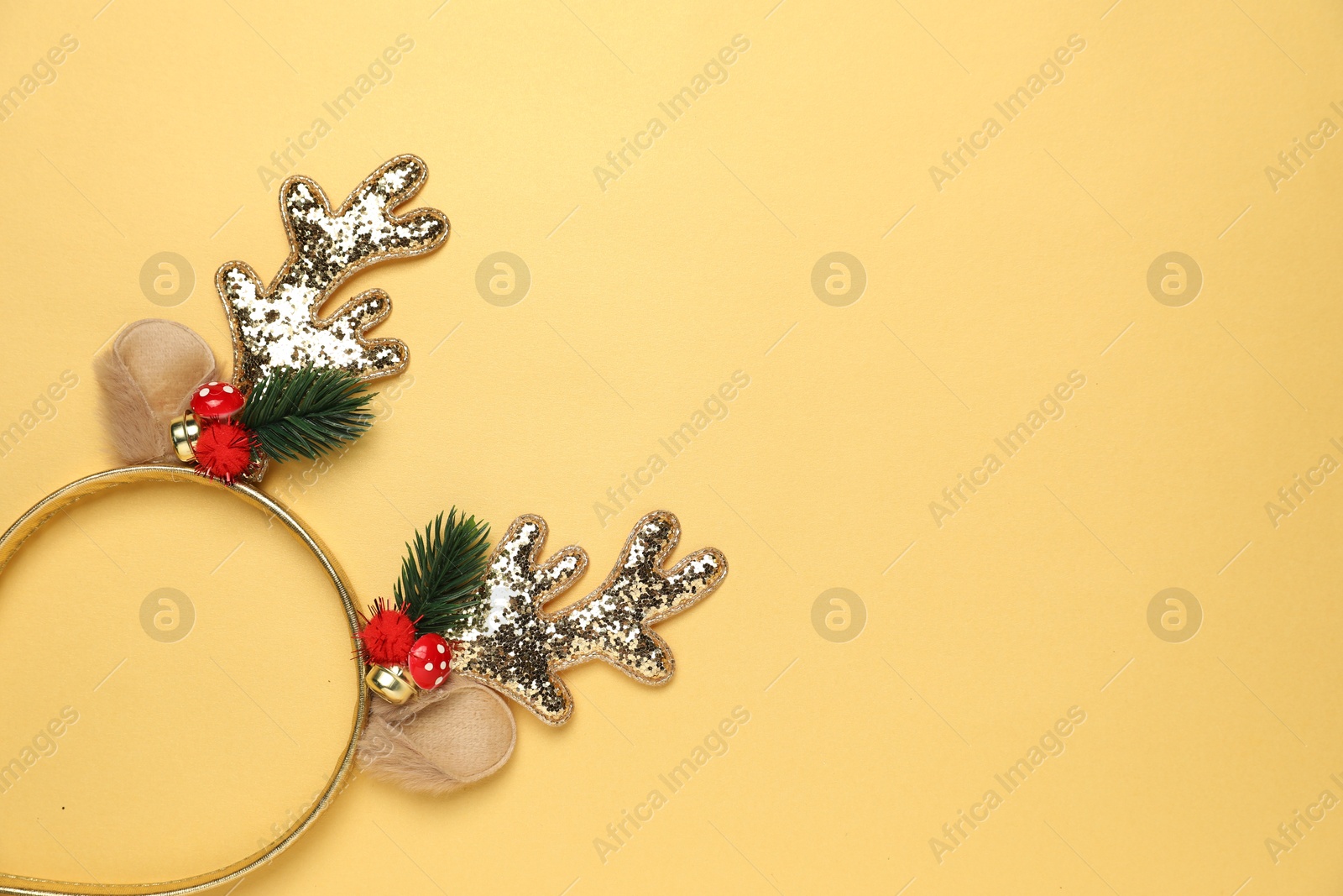 Photo of Beautiful reindeer headband on pale yellow background, top view with space for text. Christmas accessory