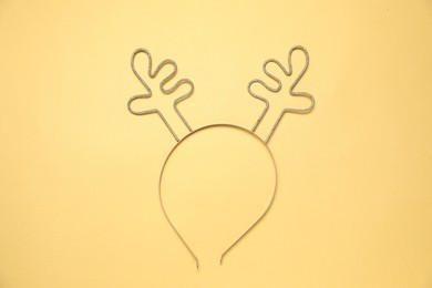 Photo of Beautiful reindeer headband on pale yellow background, top view. Christmas accessory