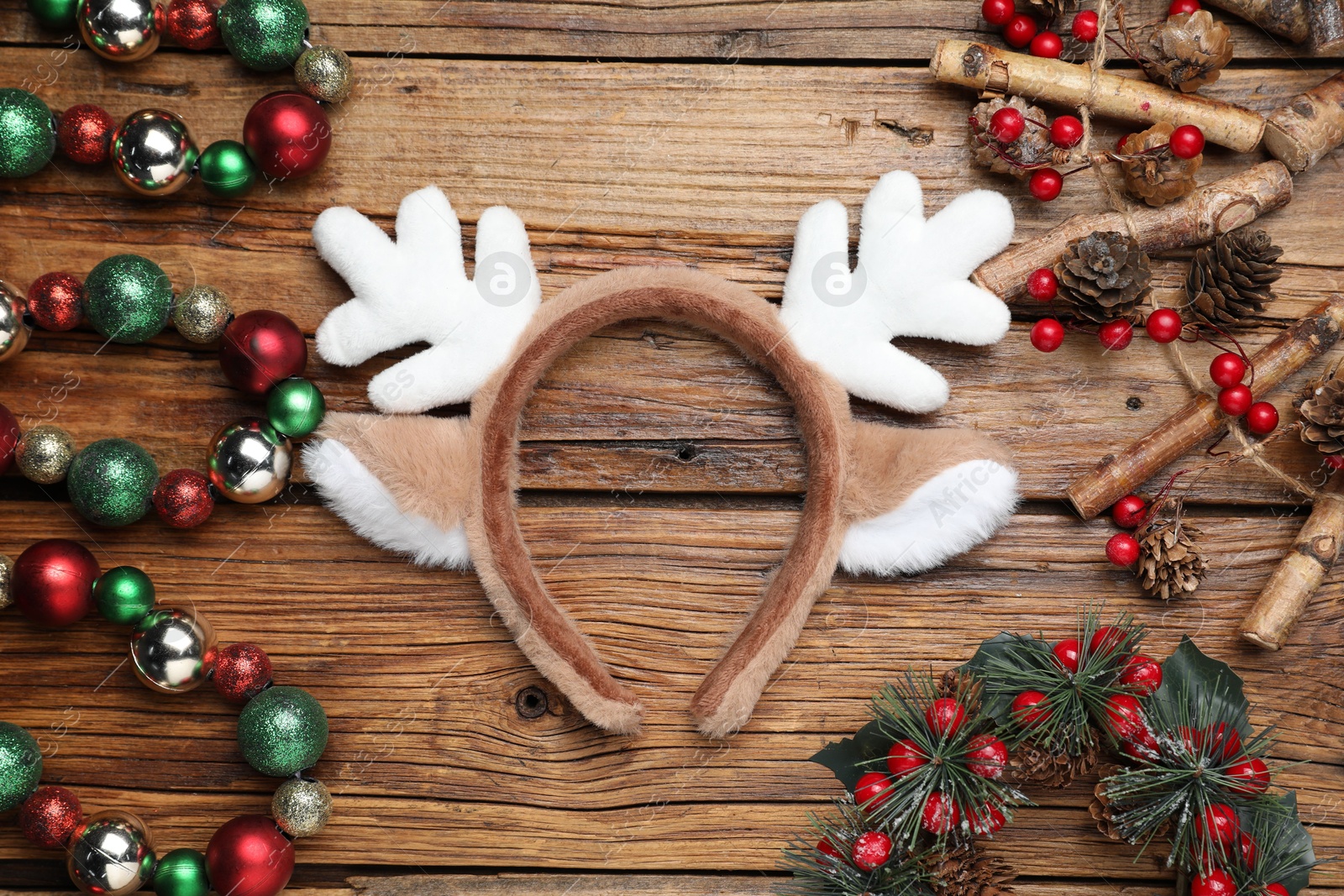 Photo of Beautiful reindeer headband and Christmas decor on wooden background, flat lay