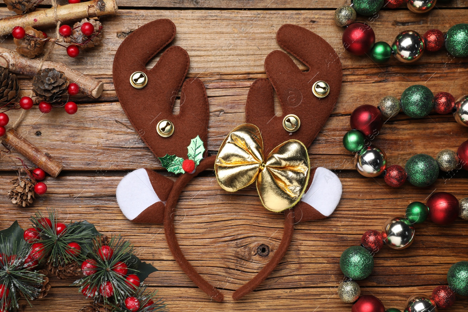 Photo of Beautiful reindeer headband and Christmas decor on wooden background, flat lay