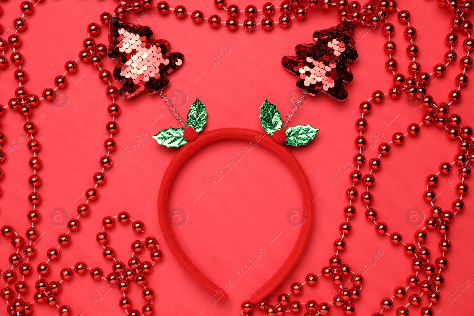 Photo of Stylish party headband and Christmas decor on red background, flat lay