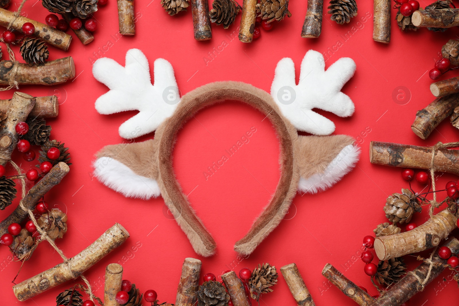 Photo of Beautiful reindeer headband and Christmas decor on red background, flat lay