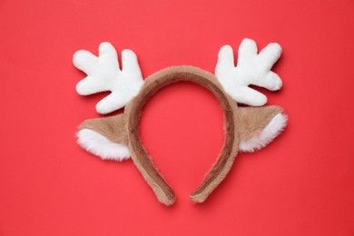 Photo of Beautiful reindeer headband on red background, top view. Christmas accessory