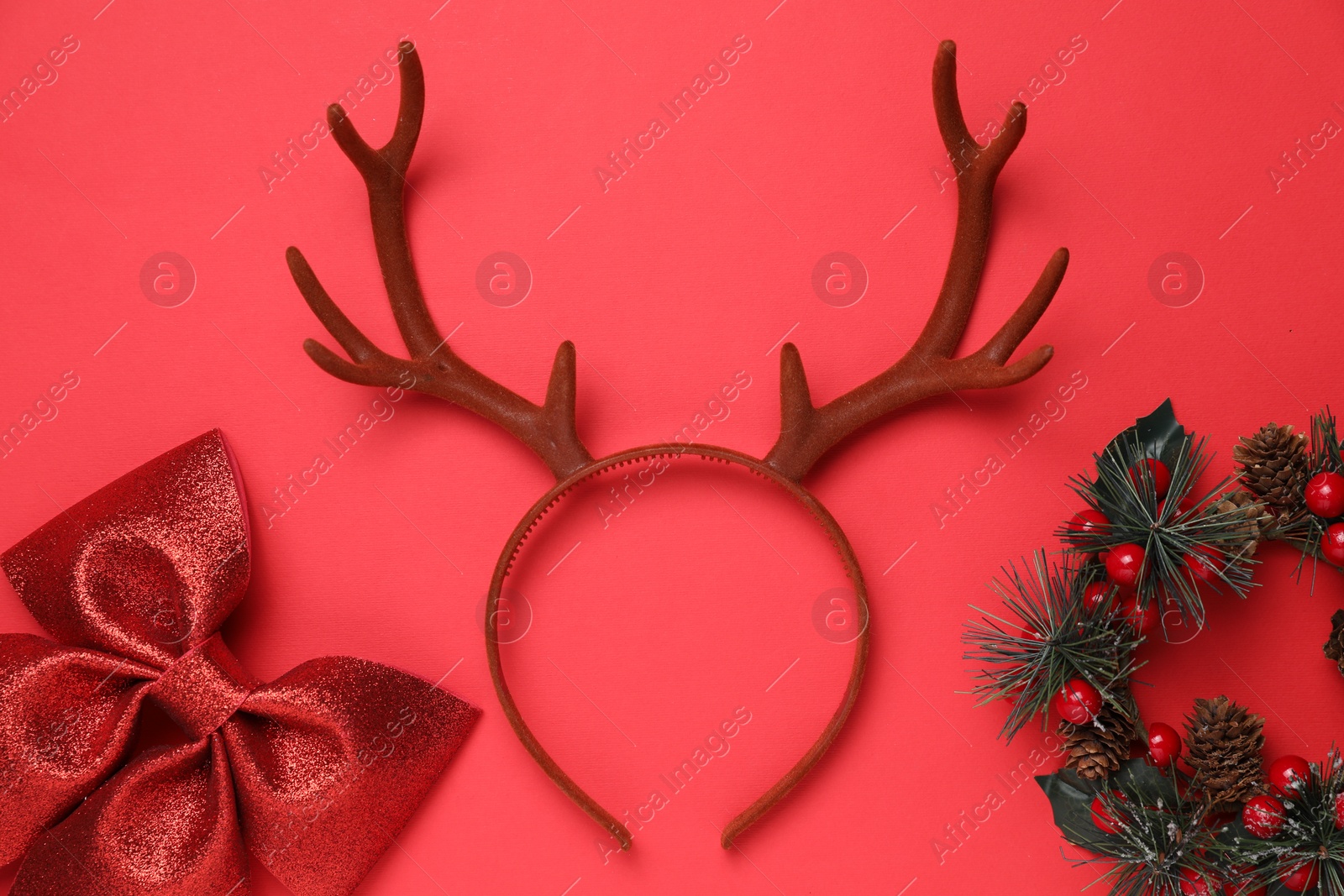 Photo of Beautiful reindeer headband and Christmas decor on red background, flat lay