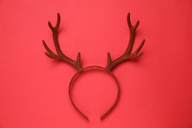 Photo of Beautiful reindeer headband on red background, top view. Christmas accessory