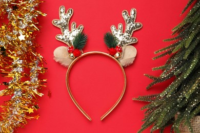 Photo of Beautiful reindeer headband and Christmas decor on red background, flat lay