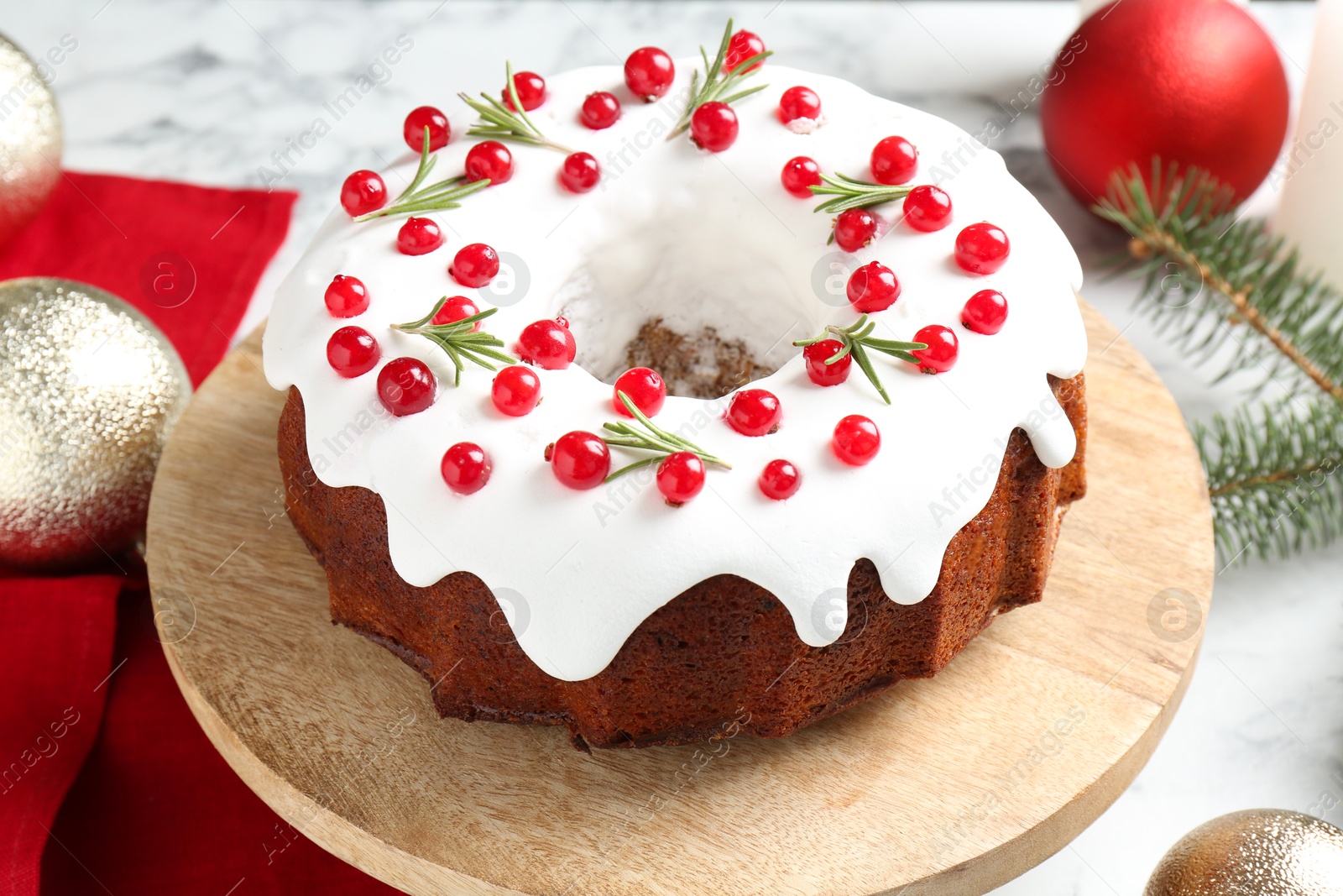 Photo of Traditional Christmas cake decorated with red currants and rosemary on white marble table, closeup