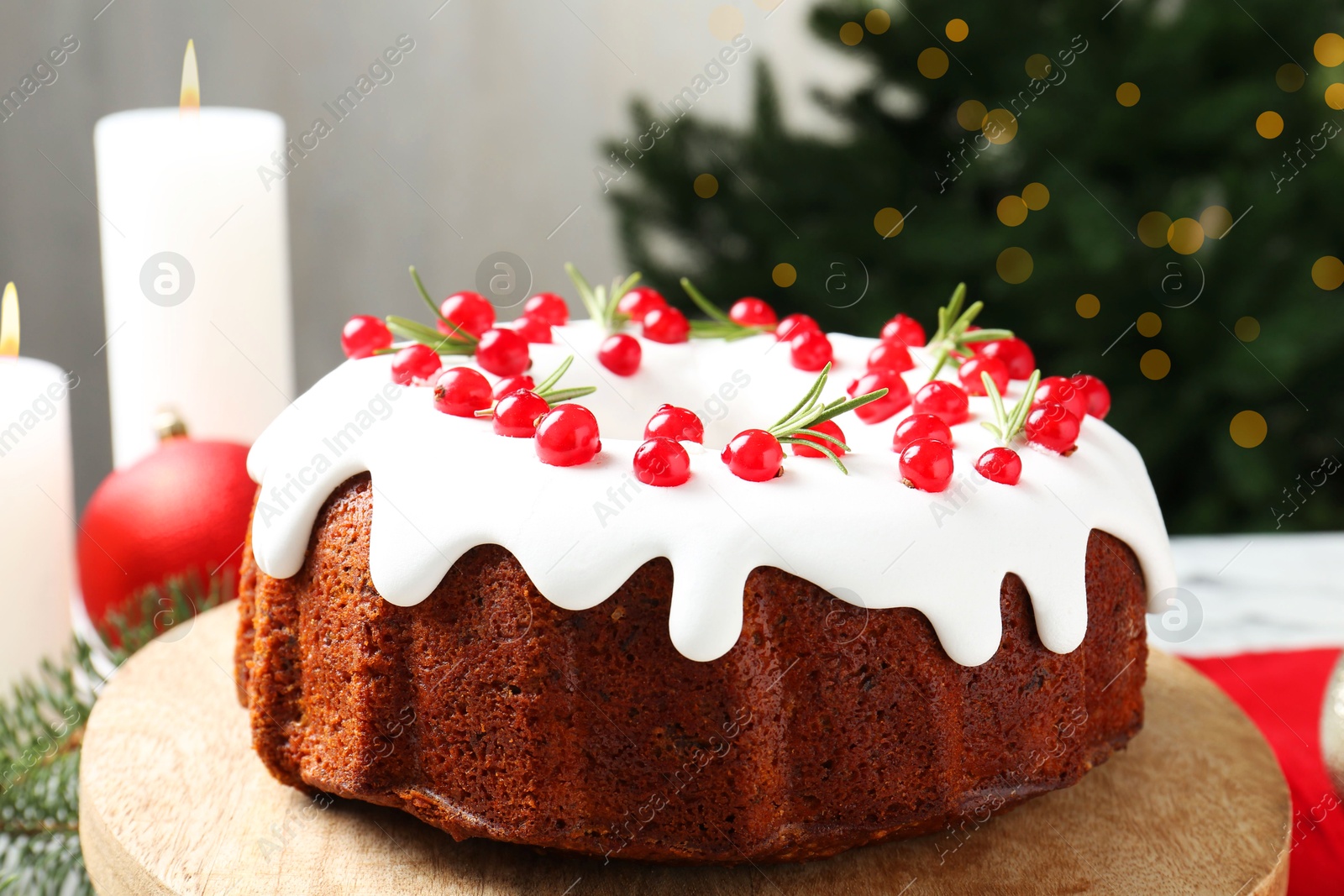 Photo of Traditional Christmas cake decorated with red currants and rosemary on table, closeup