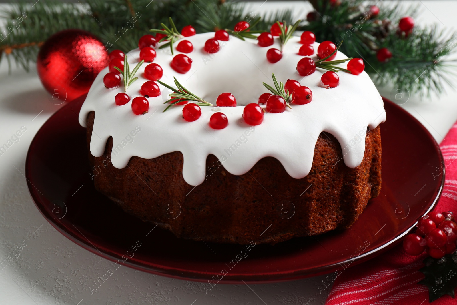 Photo of Traditional Christmas cake decorated with currants and rosemary on white table, closeup