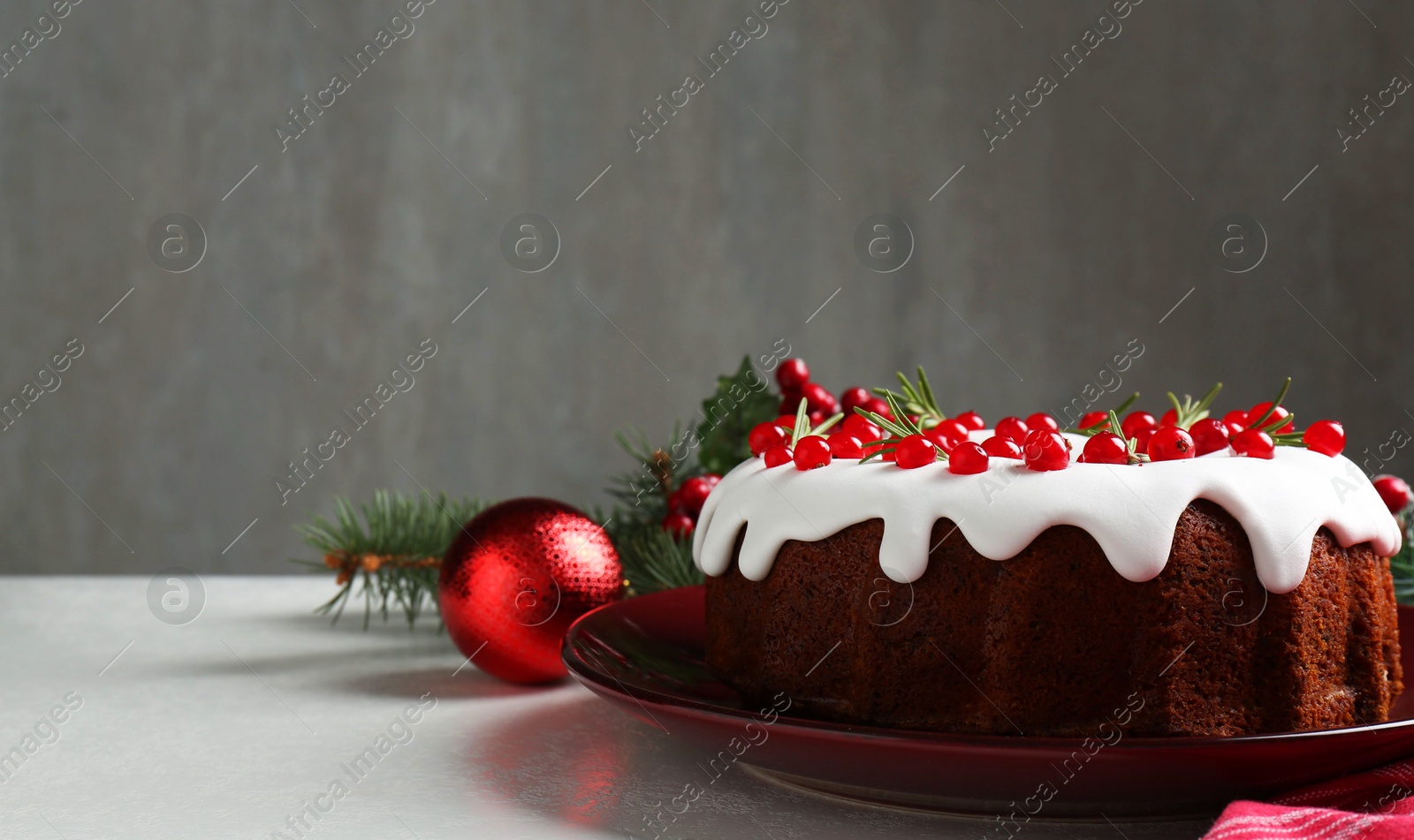 Photo of Traditional Christmas cake decorated with currants and rosemary on white table, closeup. Space for text