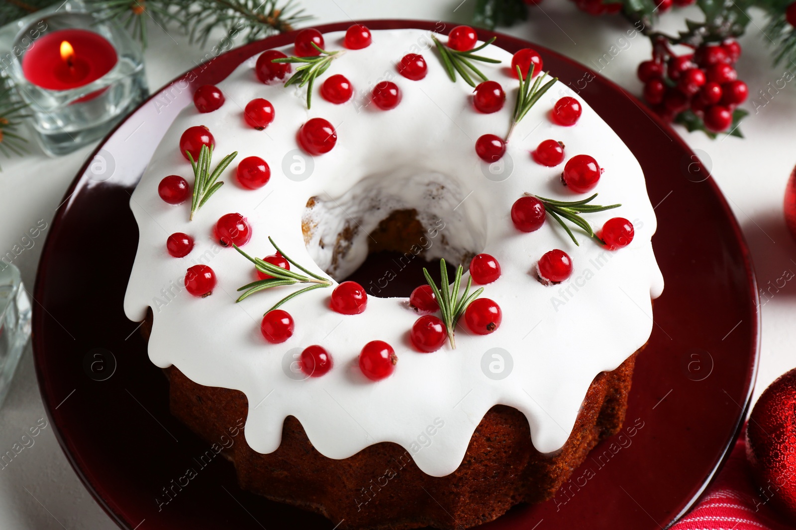 Photo of Traditional Christmas cake decorated with currants and rosemary on white table, closeup