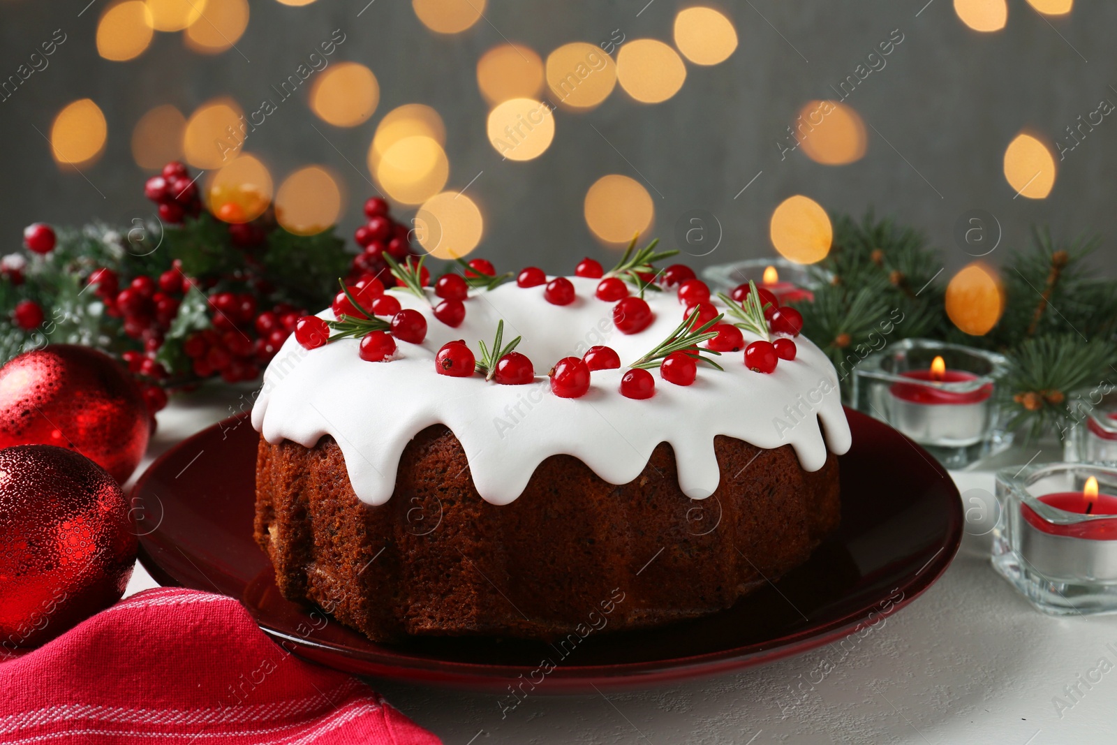 Photo of Traditional classic Christmas cake and decor on white table, closeup. Bokeh effect