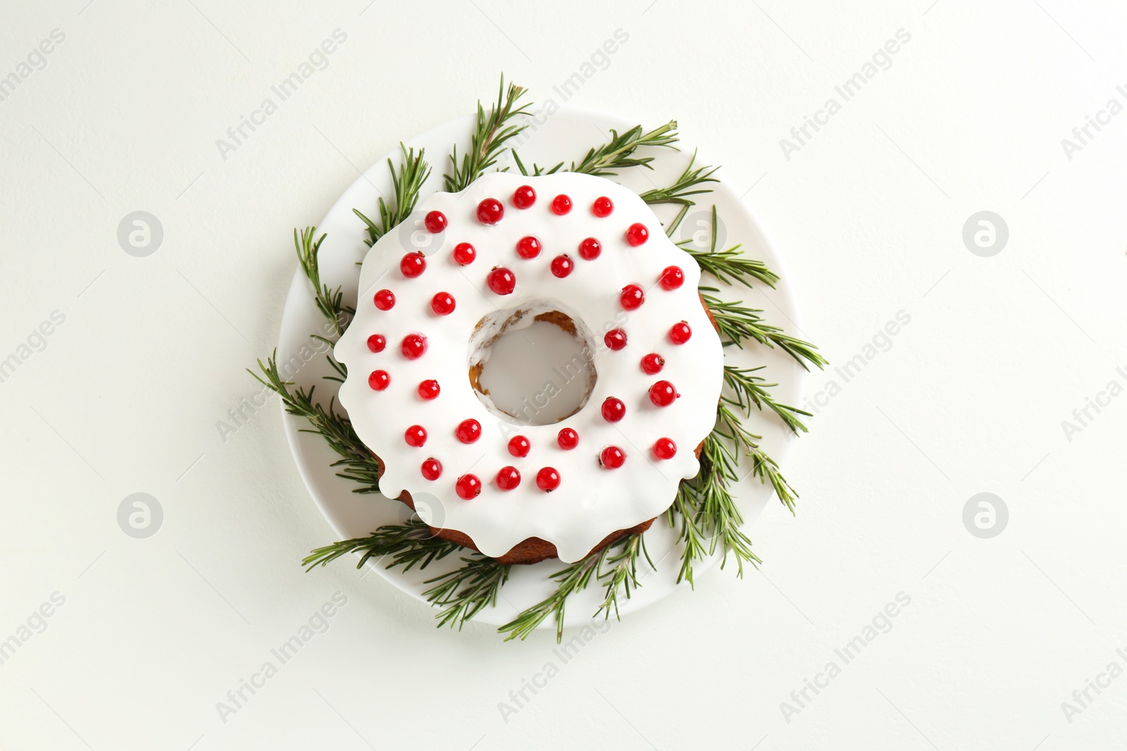 Photo of Traditional Christmas cake decorated with currants and rosemary on white table, top view