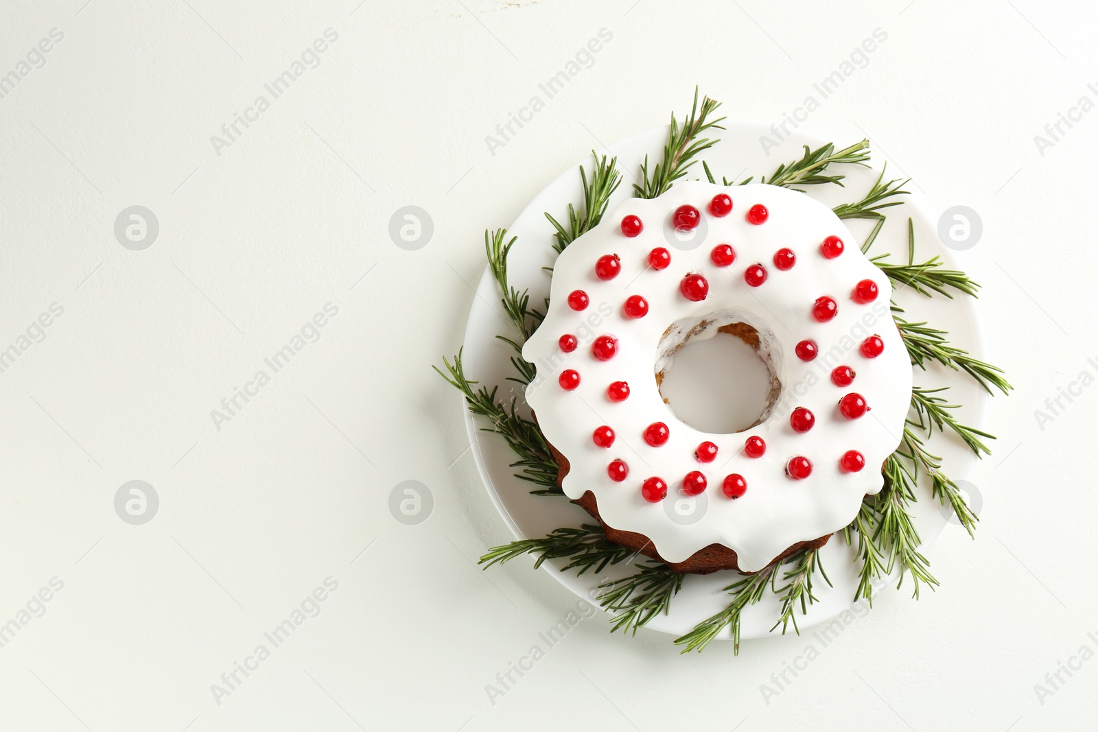 Photo of Traditional Christmas cake decorated with currants and rosemary on white table, top view. Space for text