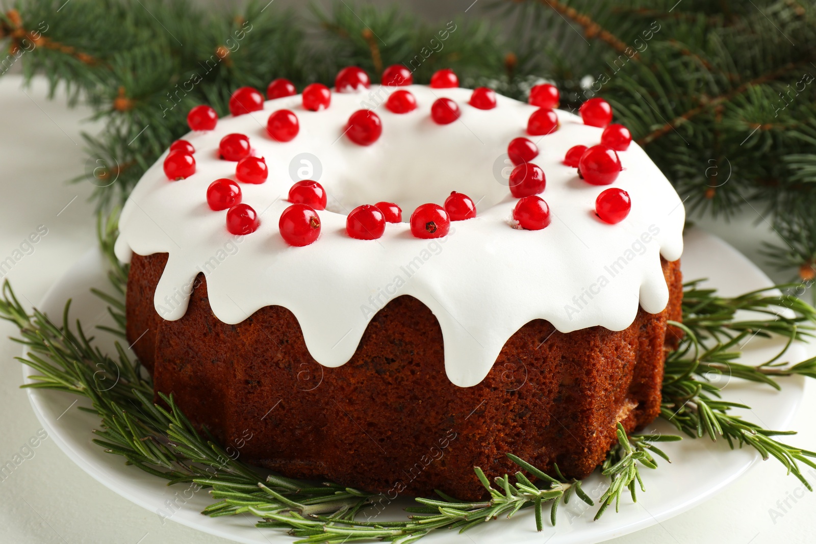 Photo of Beautifully decorated Christmas cake and fir branches on white table, closeup