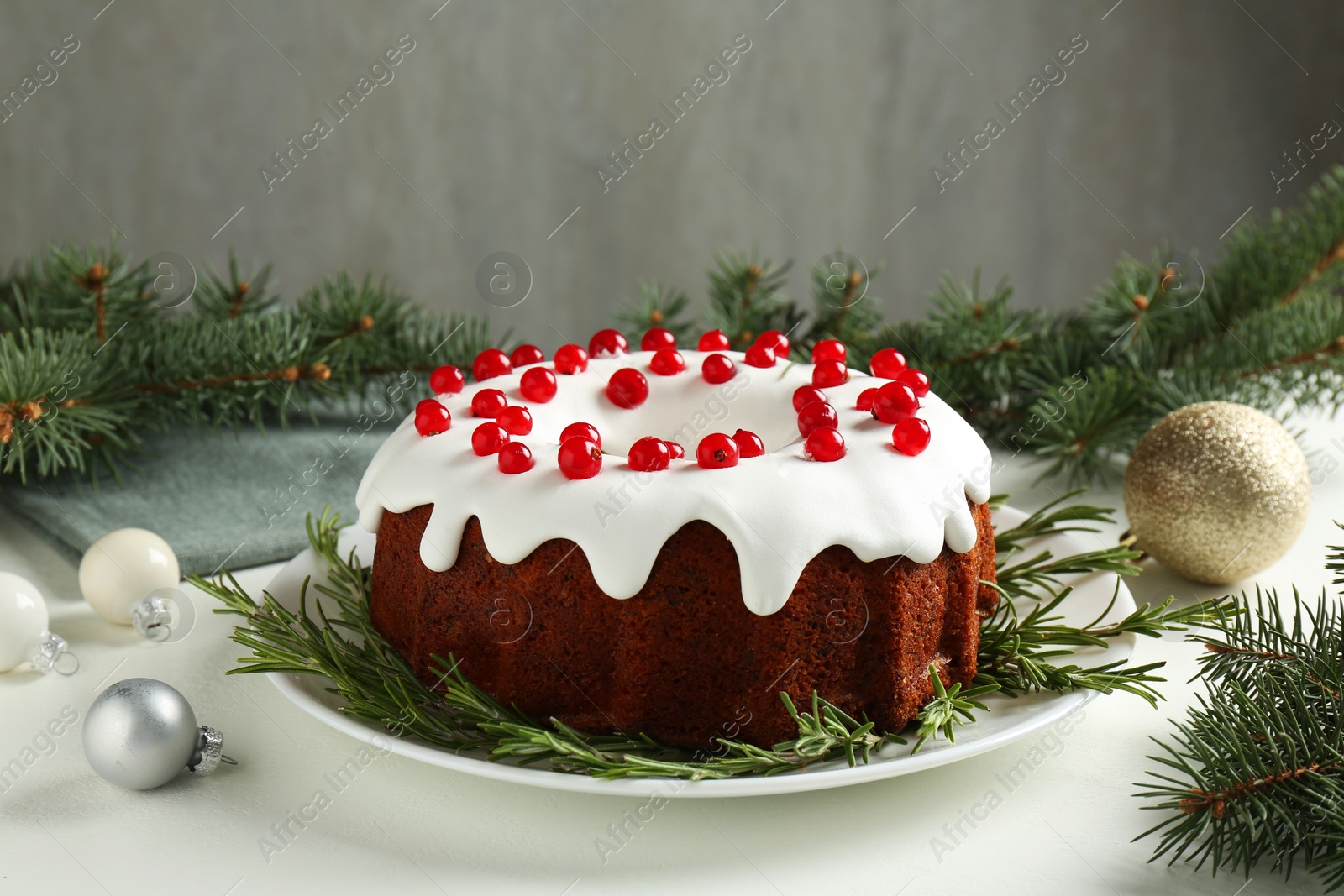 Photo of Beautifully decorated Christmas cake, fir branches and baubles on white table