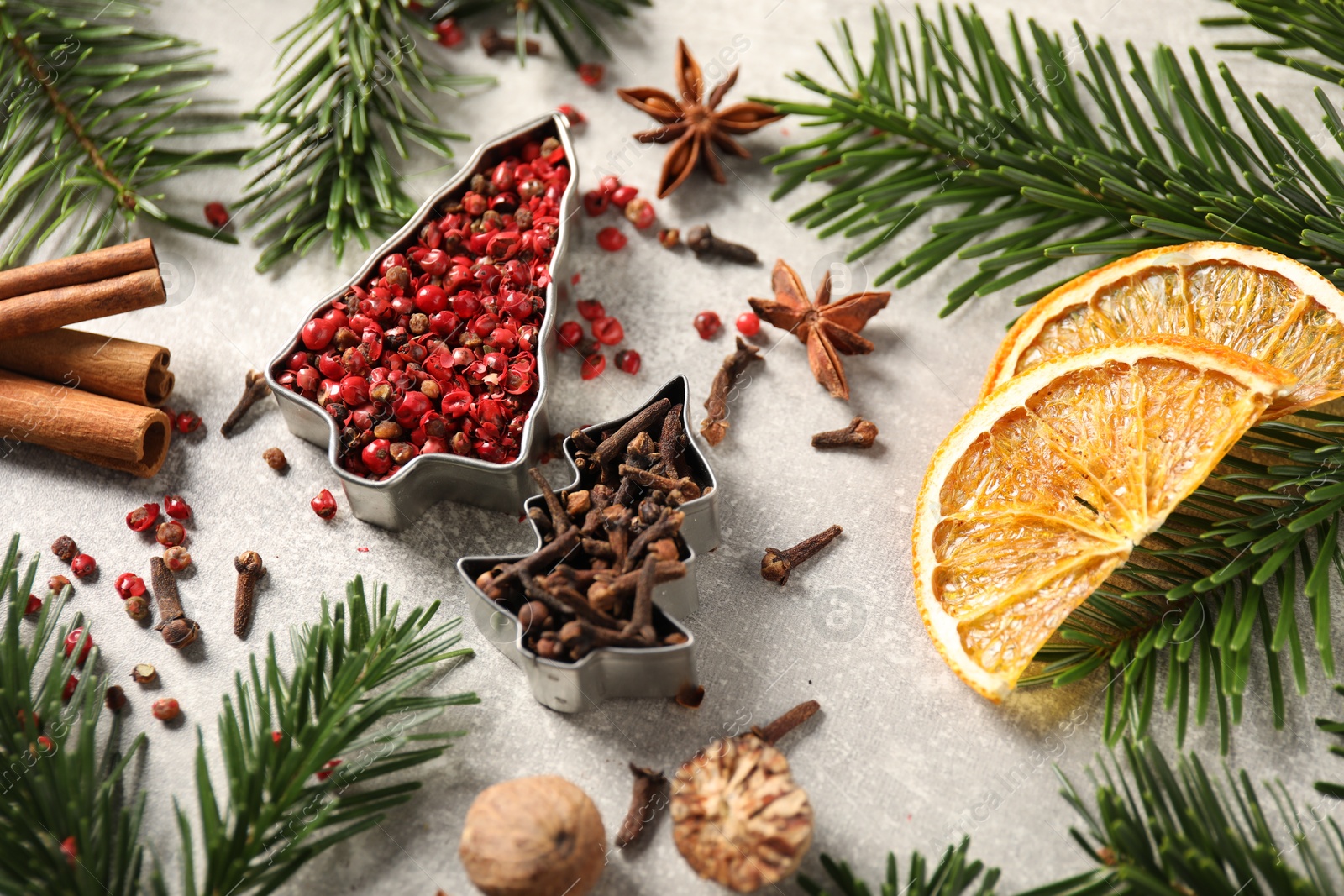 Photo of Different spices, dried orange slices and fir tree branches on light grey table. Christmas season