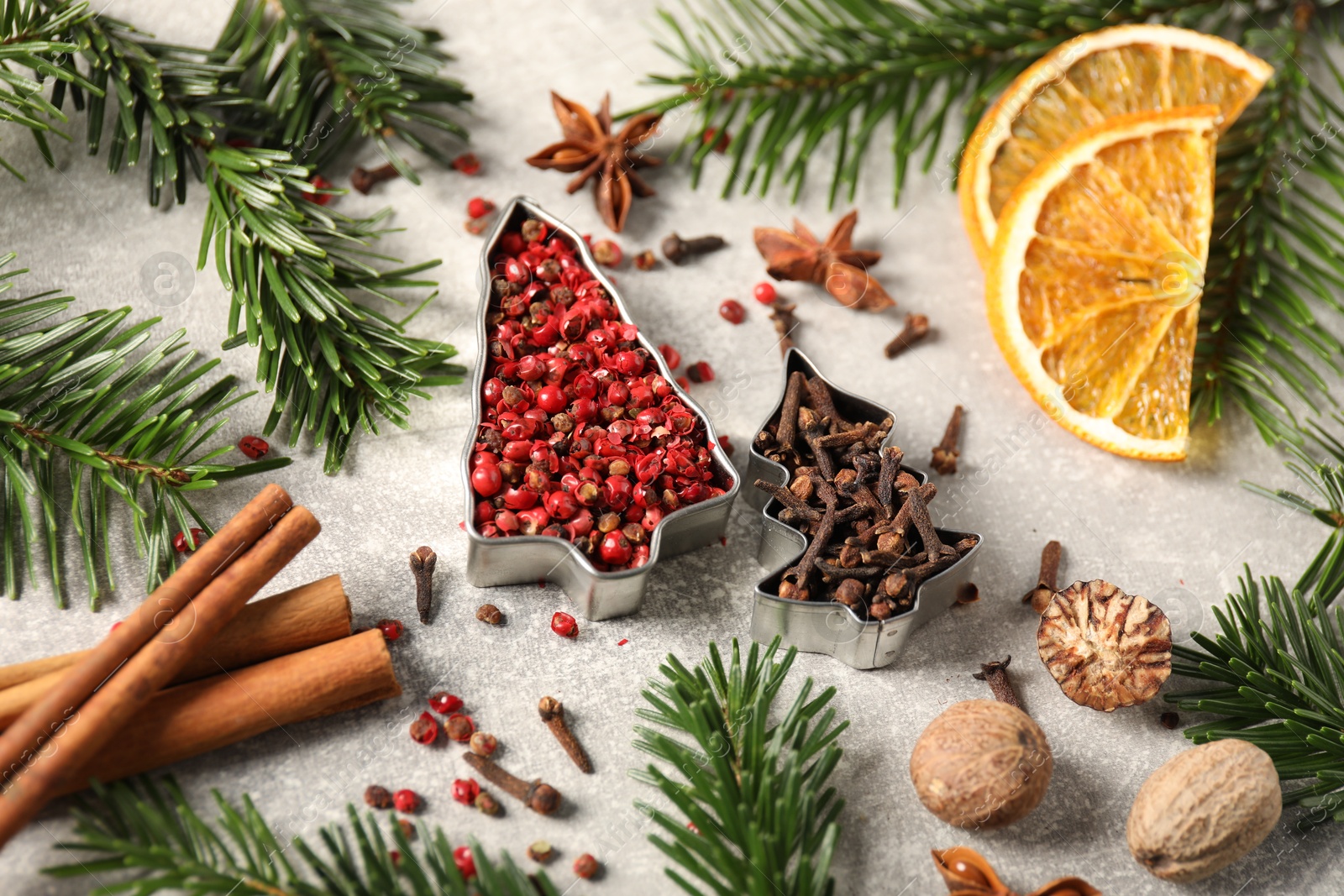 Photo of Different spices, dried orange slices and fir tree branches on light grey table. Christmas season