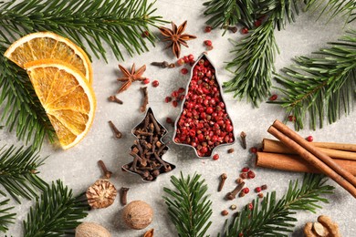 Photo of Different spices, dried orange slices and fir tree branches on light grey table, flat lay. Christmas season