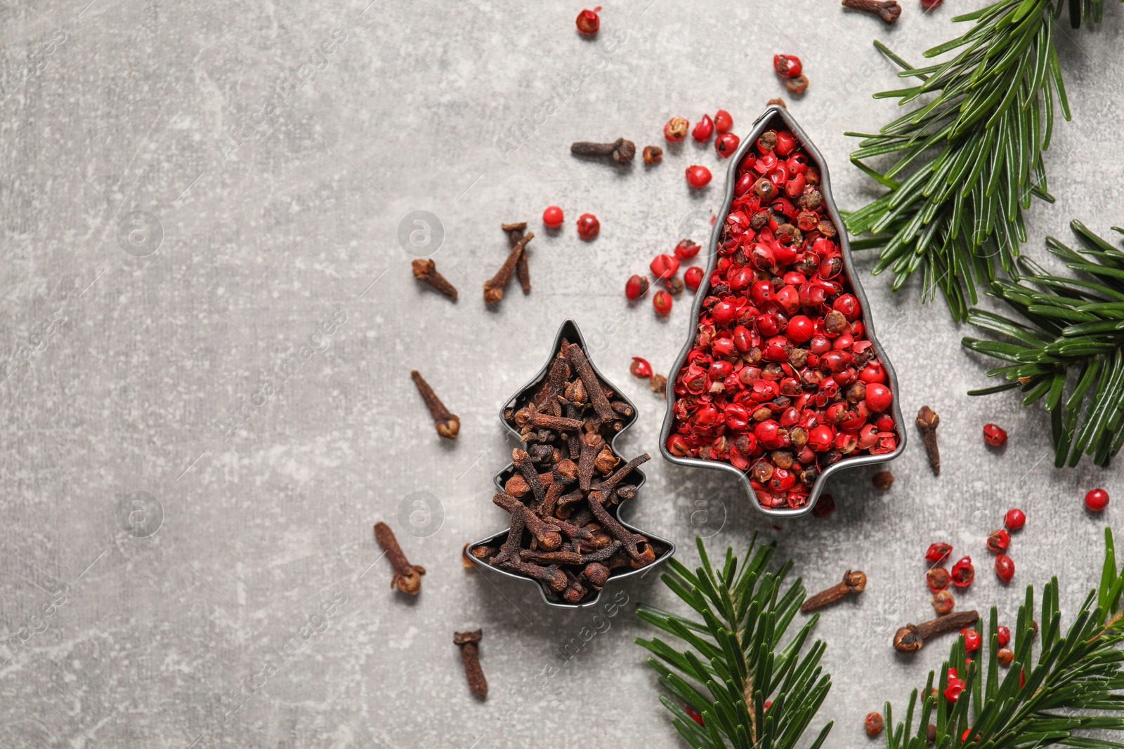 Photo of Different spices and fir tree branches on light grey table, flat lay with space for text. Christmas season