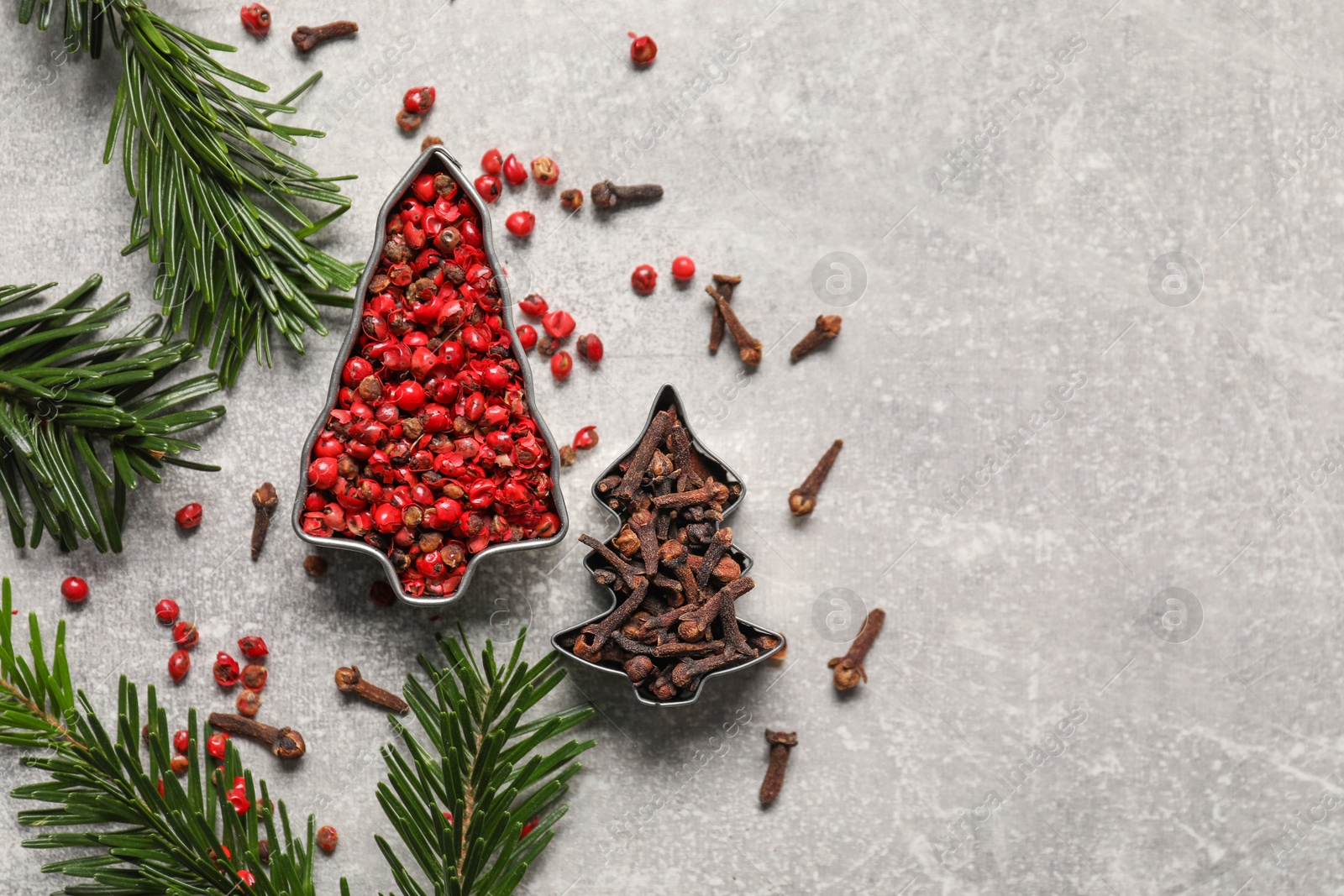 Photo of Different spices and fir tree branches on light grey table, flat lay with space for text. Christmas season