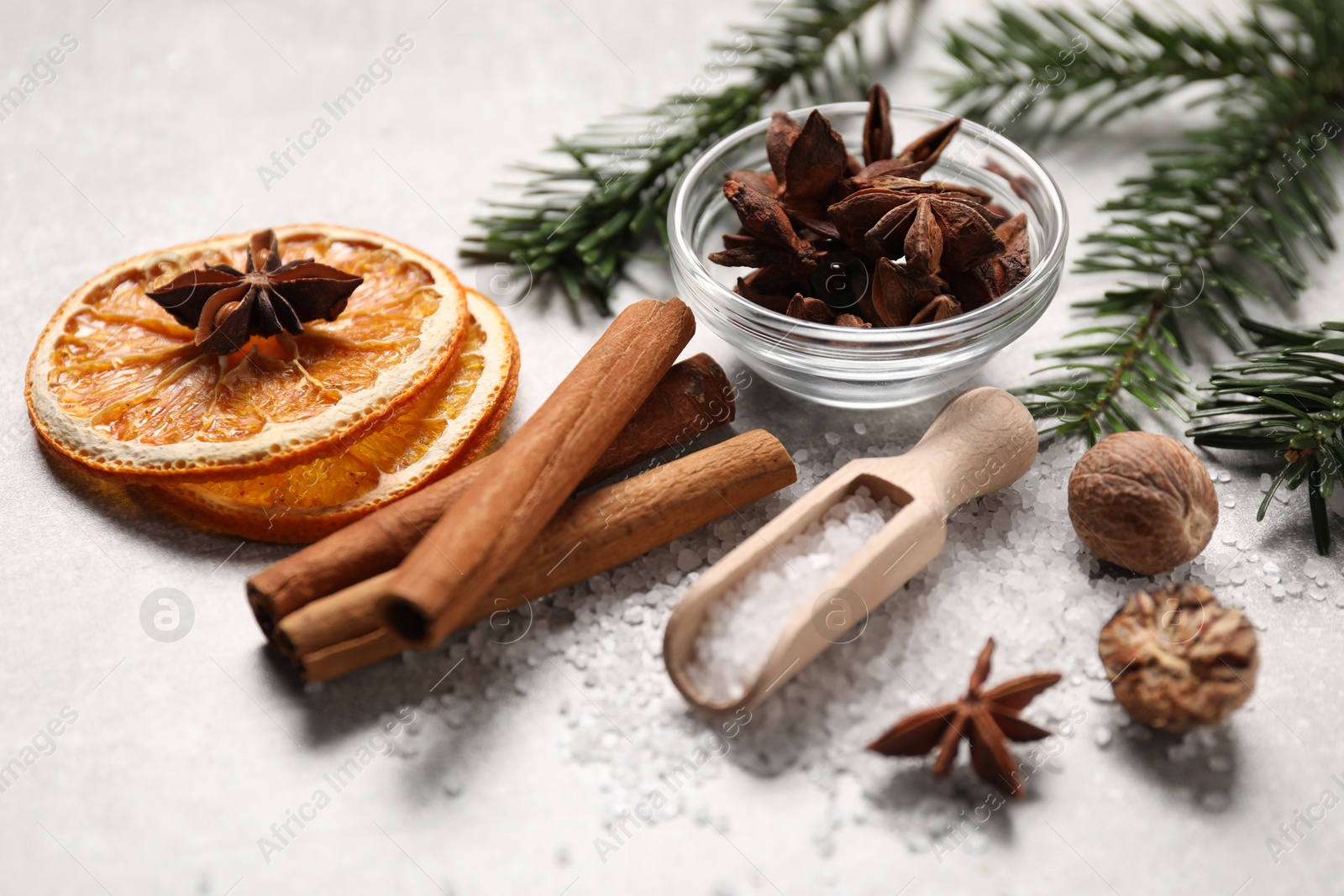 Photo of Different spices, dried orange slices and fir tree branches on light grey table, closeup. Christmas season