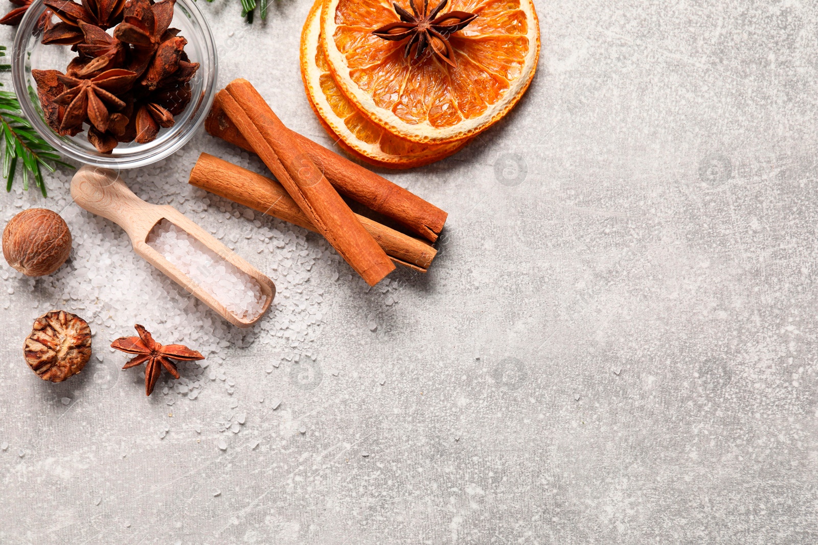 Photo of Different spices and dried orange slices on light grey table, flat lay with space for text. Christmas season