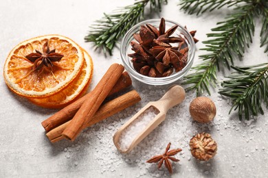 Photo of Different spices, dried orange slices and fir tree branches on light grey table. Christmas season