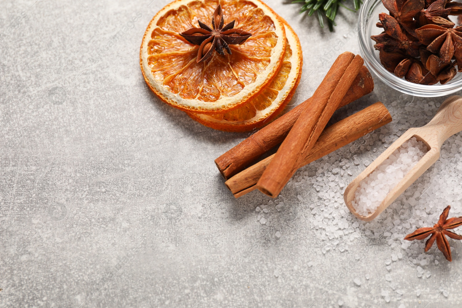 Photo of Different spices and dried orange slices on light grey table, flat lay with space for text. Christmas season