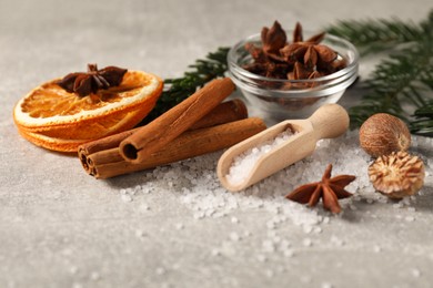 Photo of Different spices, dried orange slices and fir tree branches on light grey table, closeup. Christmas season