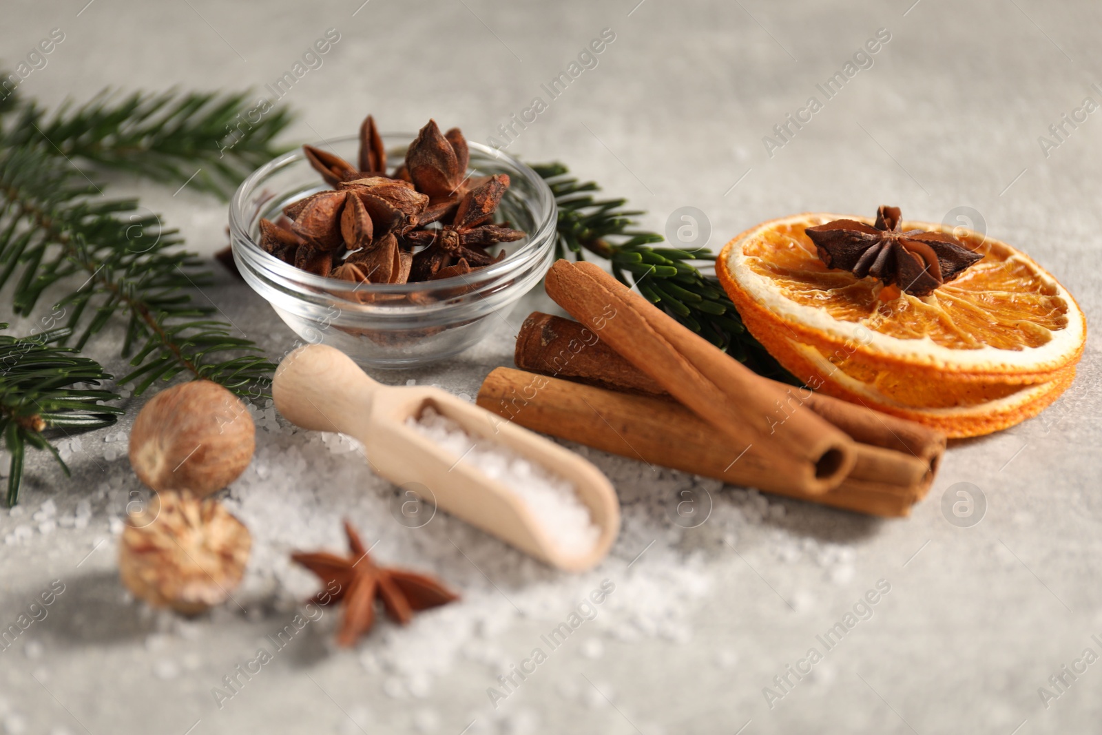 Photo of Different spices, dried orange slices and fir tree branches on light grey table, closeup. Christmas season