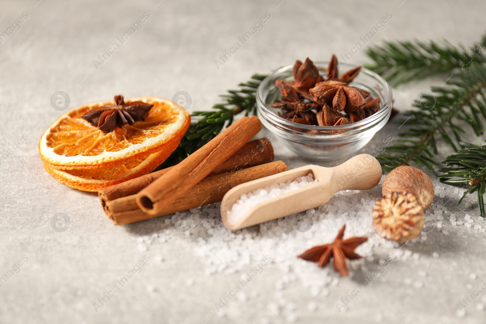 Photo of Different spices, dried orange slices and fir tree branches on light grey table, closeup. Christmas season